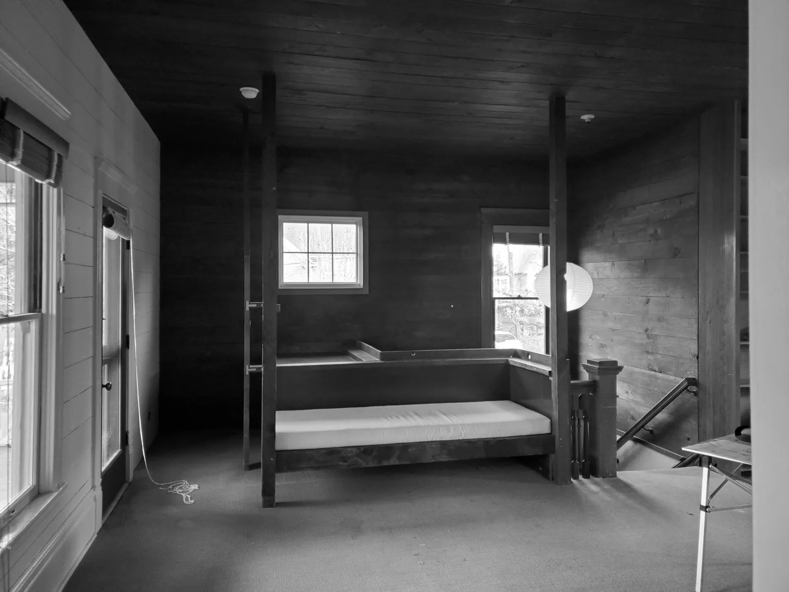 A built-in bench seating area is situated near windows and a stairway in a wood-paneled room.