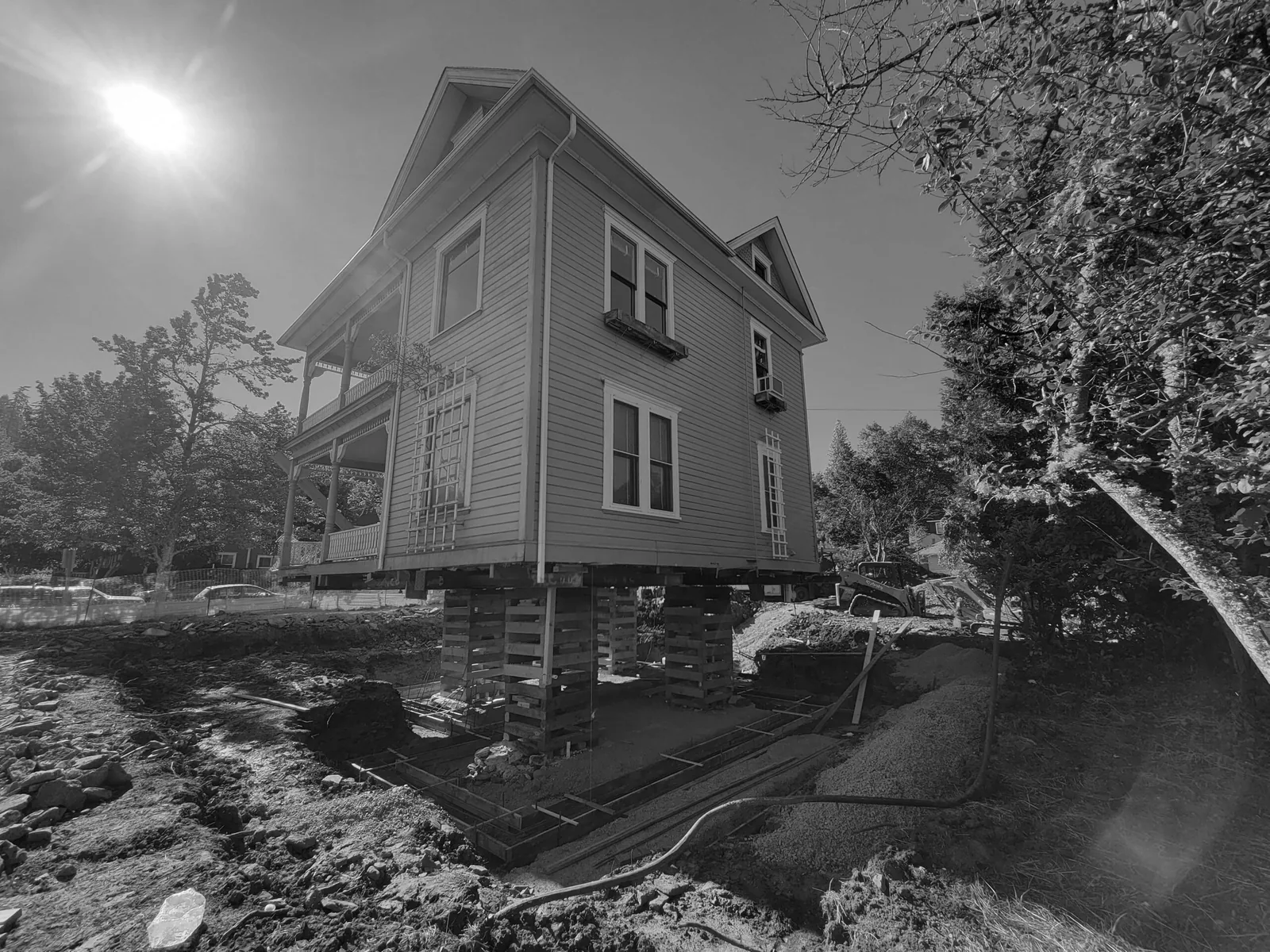 Queen Anne style house elevated on stacked supports for foundation renovation work.