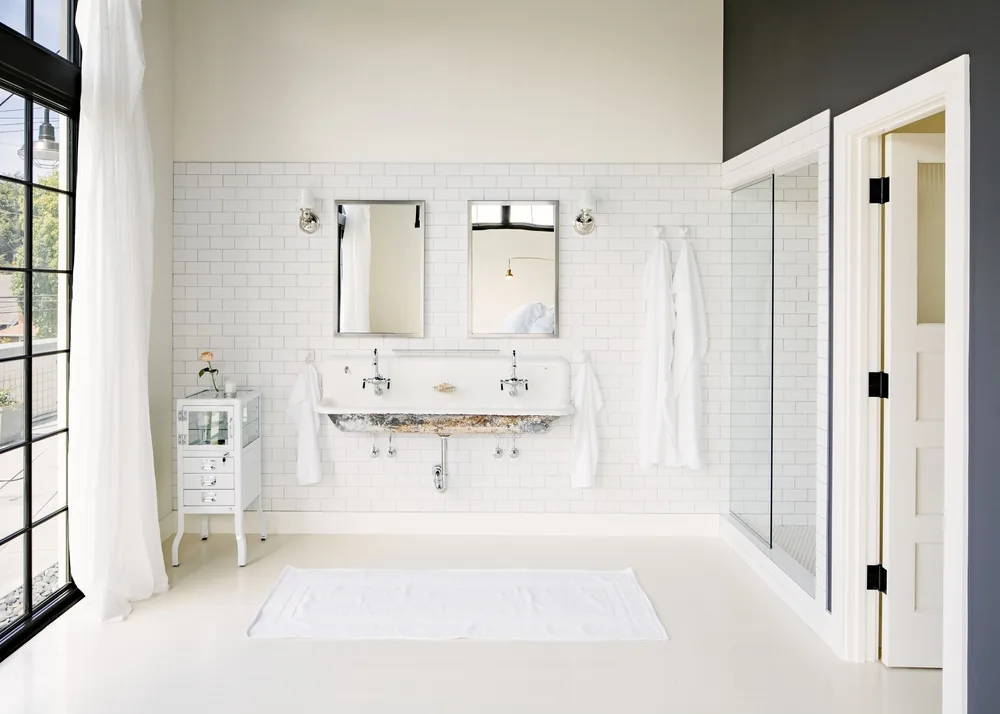Bathroom of Division Street Residence with subway tiles, white fixtures, and black steel window frames reflects industrial style.