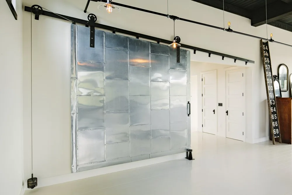 Room features a large metal sliding door on a black track with white walls and floors.