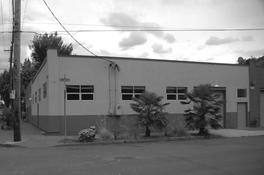 Exterior front of Division Street Residence shows a flat roof and industrial window design at the street corner.