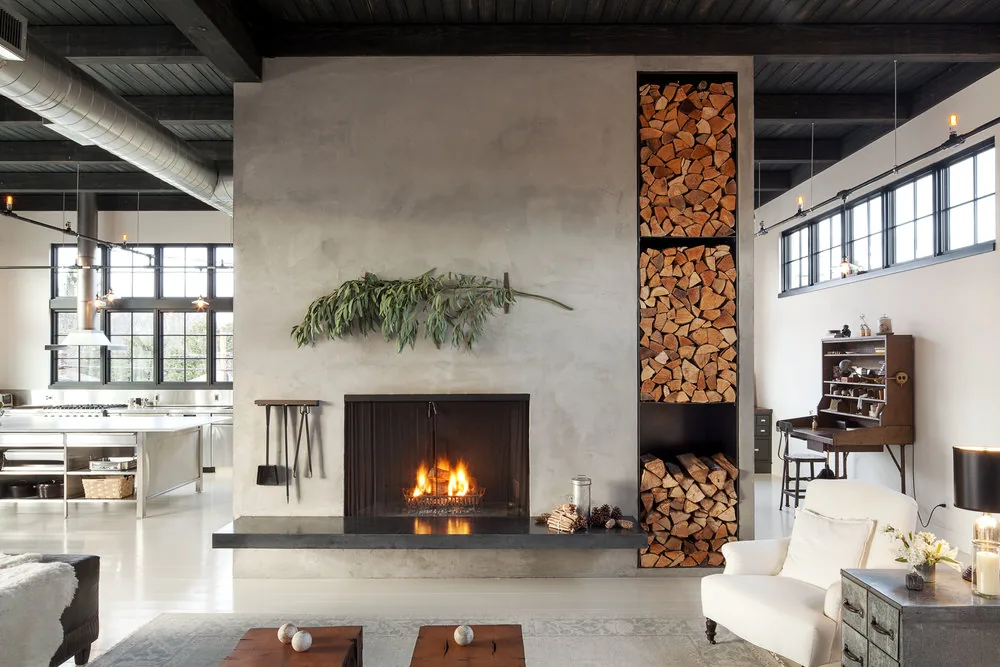 Living room of Division Street Residence features a concrete fireplace with vertical wood storage niche and industrial steel windows.