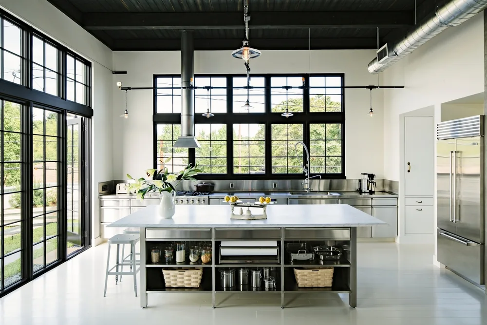 Kitchen with black metal-framed windows, stainless steel cabinets, and a central island with open shelving.