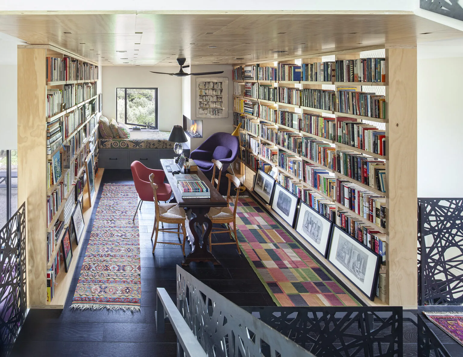 Library room with built-in bookshelves, reading seating, and decorative rugs at Ojai Residence by Frederick Fisher and Partners