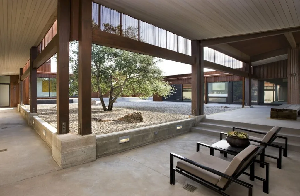 The Santa Ynez Residence features a covered patio with concrete flooring and a central gravel courtyard with natural landscaping.