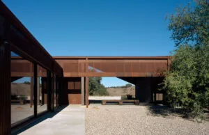 Courtyard exterior featuring rust-colored metal cladding and large glass windows with gravel ground covering.
