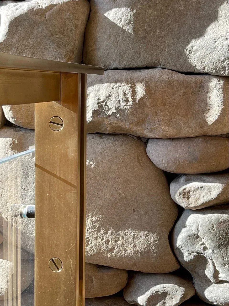 Brass structural detail mounted on a rough stone wall.