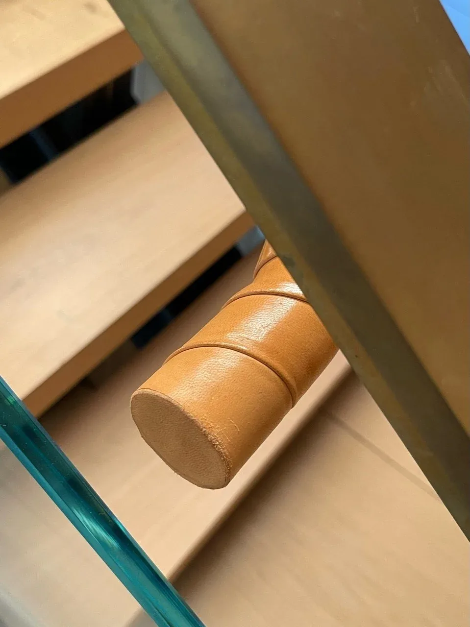 Detail of a leather-wrapped handle mounted on a metal frame beside wooden steps.