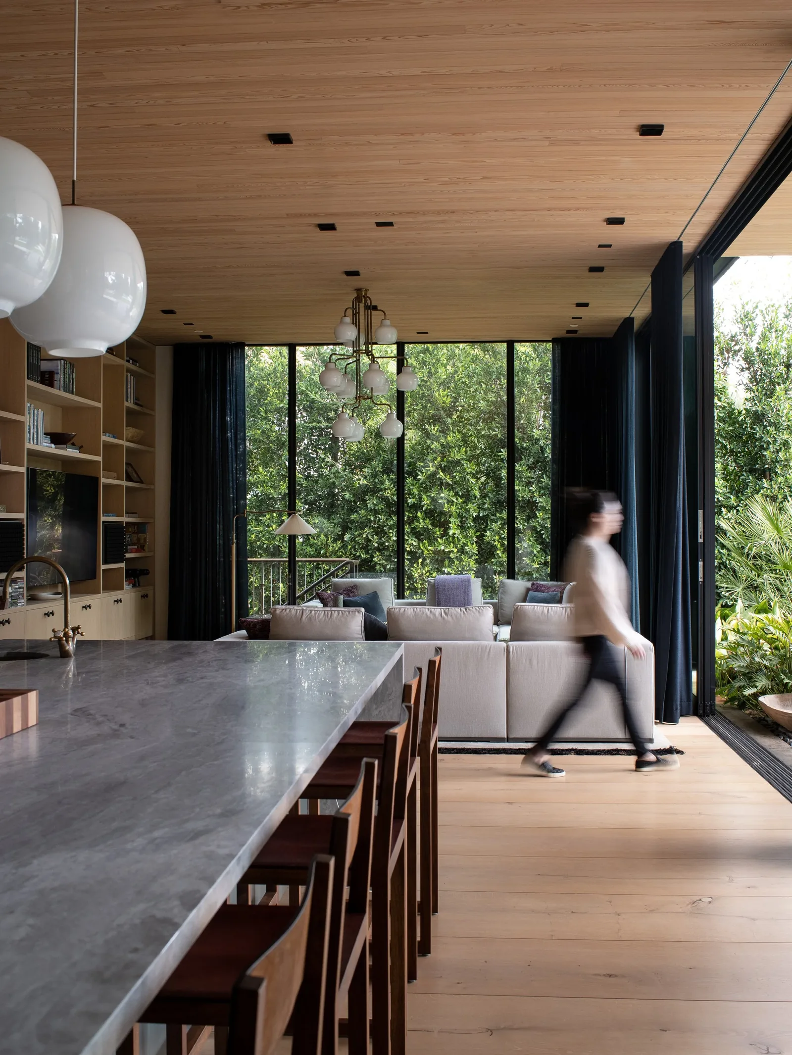 Modern living room and kitchen with floor-to-ceiling glazing and wood-paneled ceiling