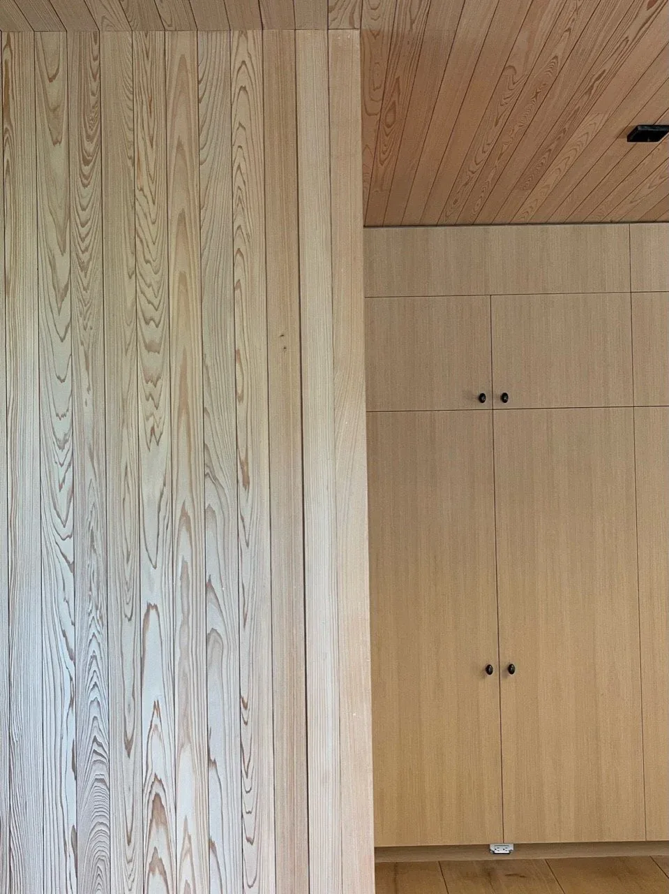 Light wood paneling and cabinetry create a seamless interior surface on wall and ceiling.