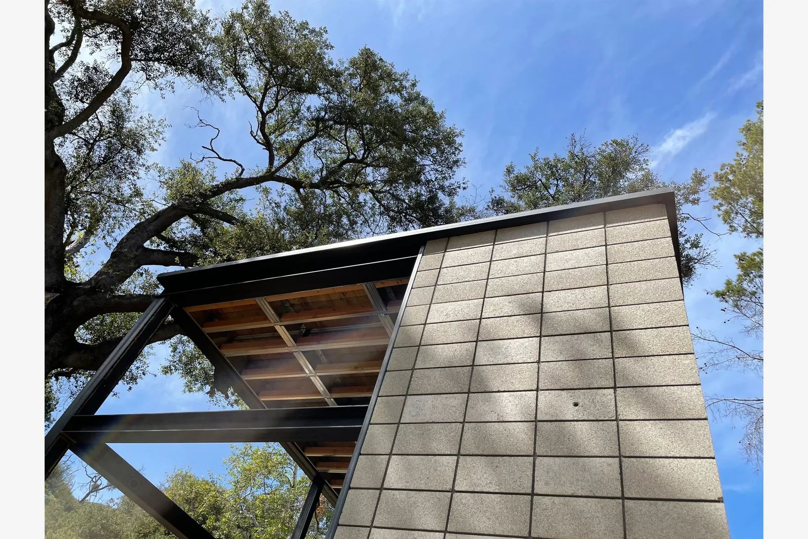 Modern building under a clear sky features cinder block exterior walls with steel framing and a flat roof.