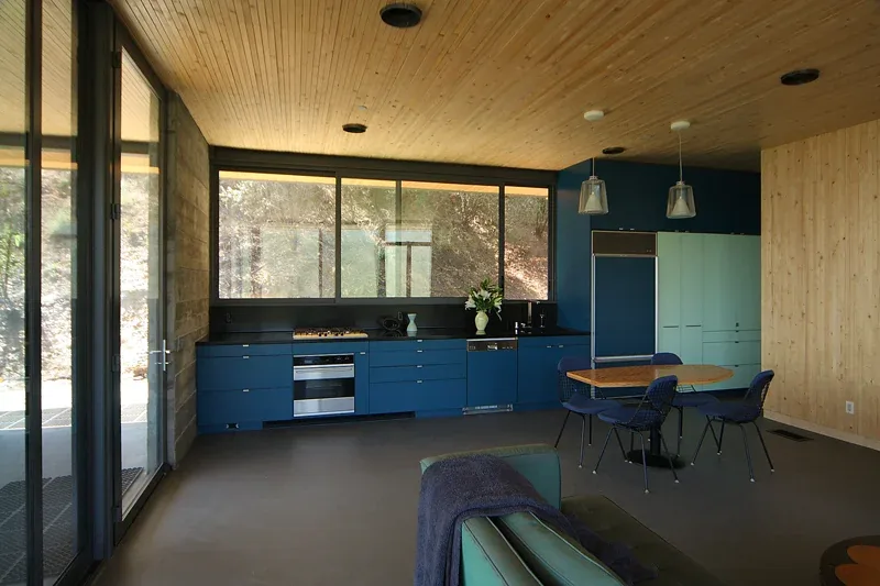 Modern kitchen interior with blue cabinetry and wood-paneled ceiling and walls.