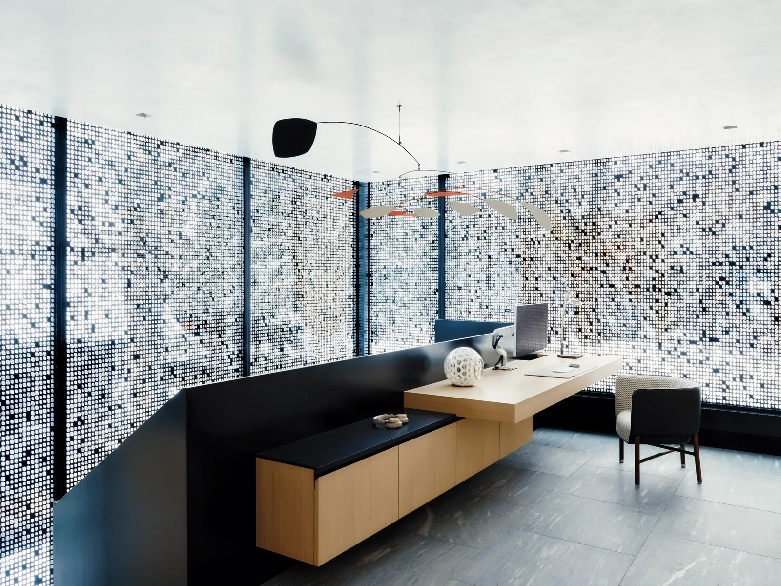 Office space featuring a floating desk and pixelated pattern window screens providing diffused natural light.