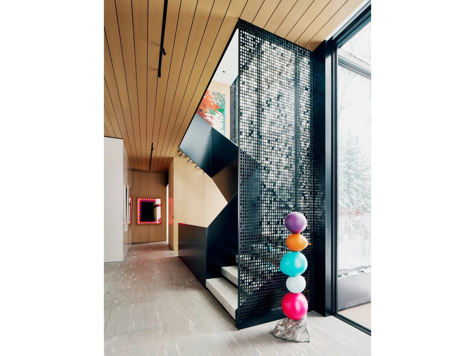 Modern interior hallway with perforated metal staircase and wood-paneled ceiling.