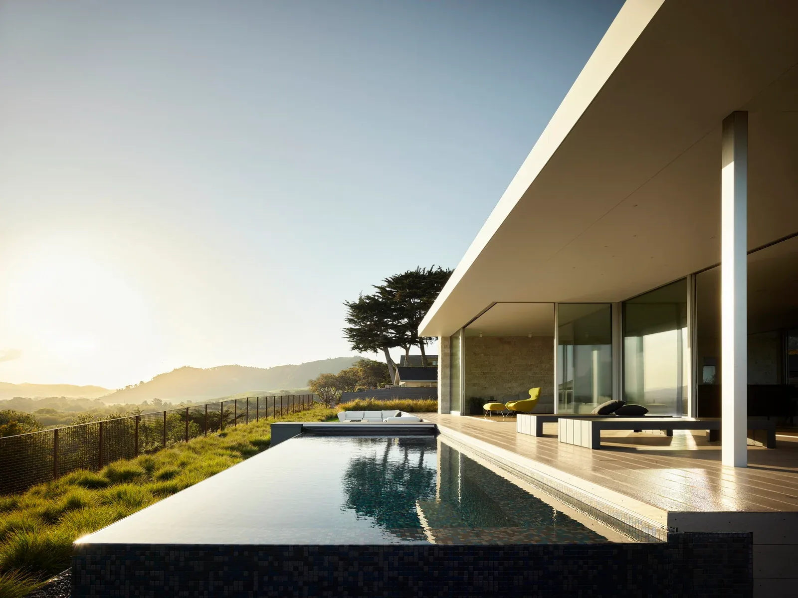 Ribera Road house features an infinity pool adjacent to a flat-roofed pavilion with extensive glazing.