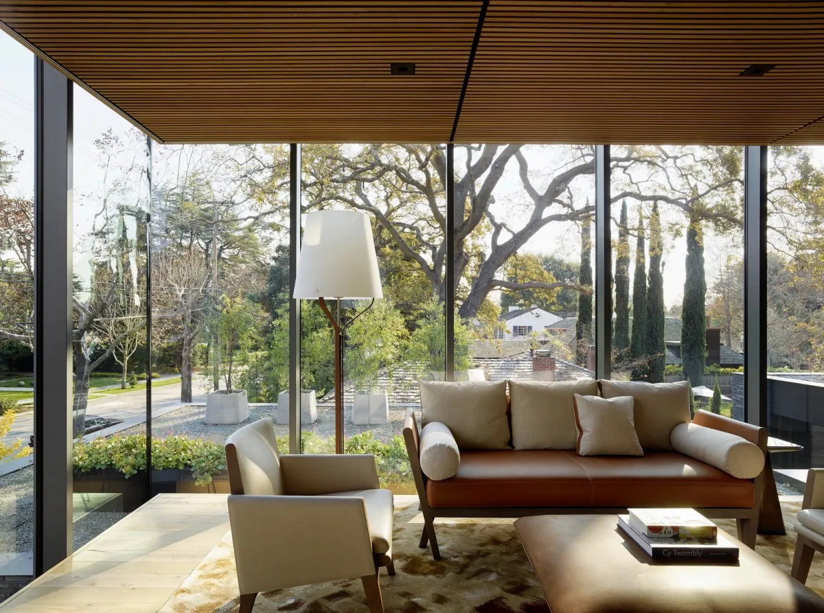 Living room with floor-to-ceiling glazing features a wooden slatted ceiling and modern seating furniture.