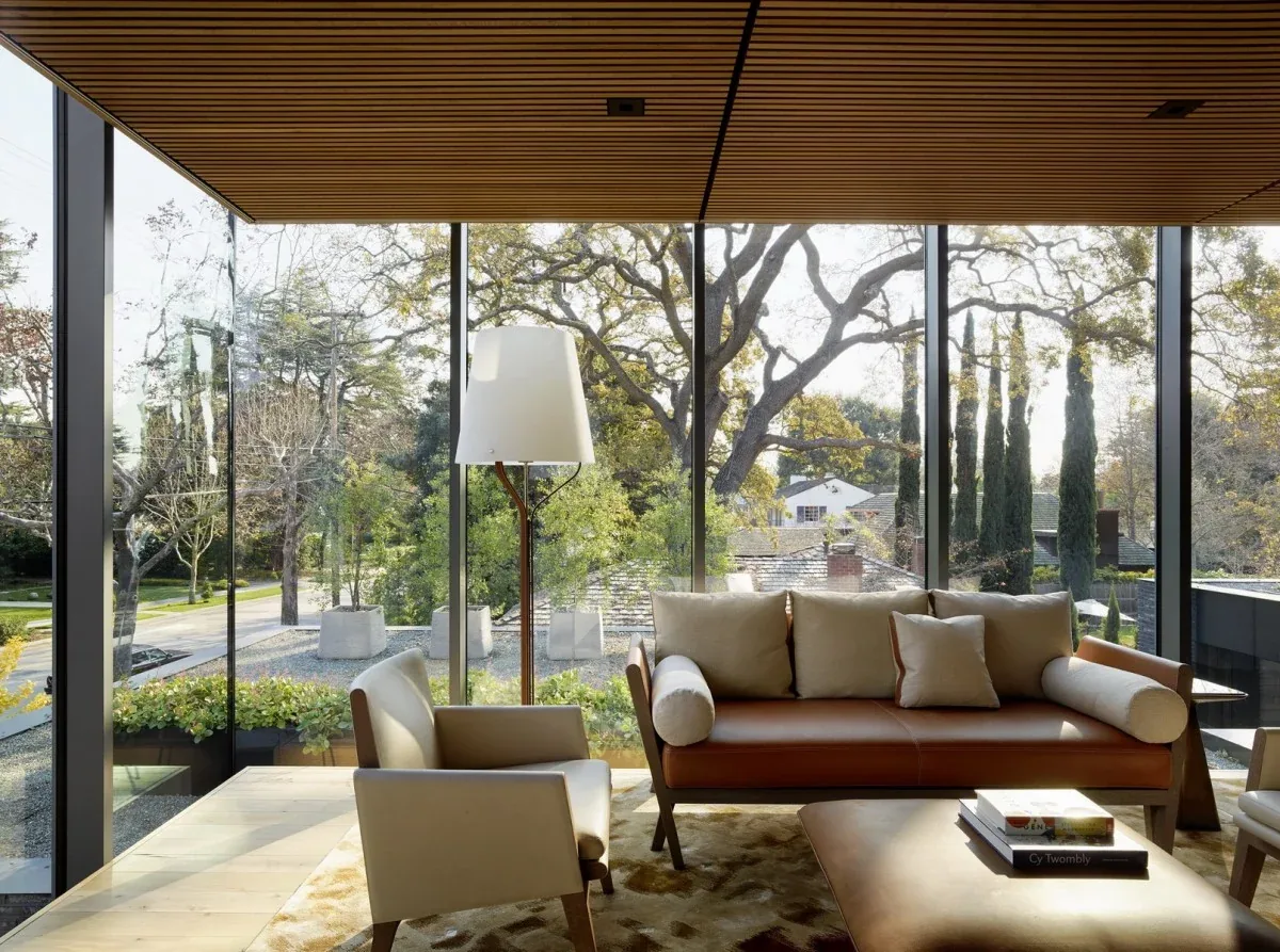 Living room with floor-to-ceiling glass windows and leather sofa with cushions.