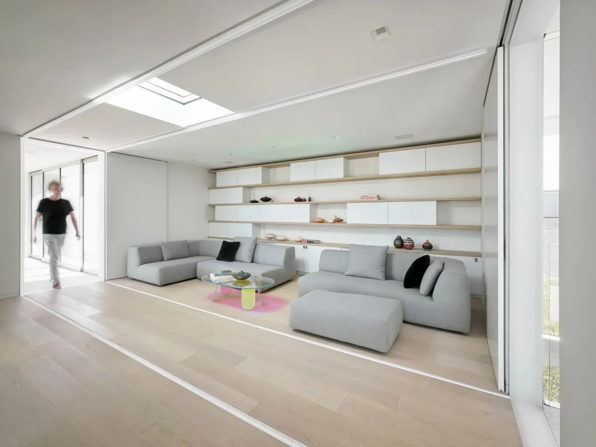 Living room featuring built-in floating shelves, gray sofas, and a skylight in the ceiling.