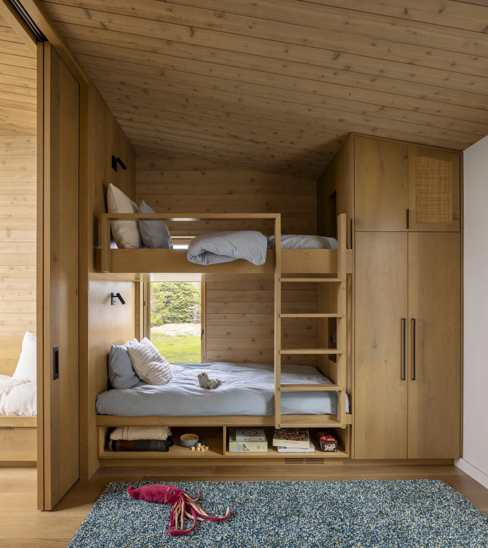 Bedroom with custom wood bunk beds and built-in wardrobes in a coastal home.