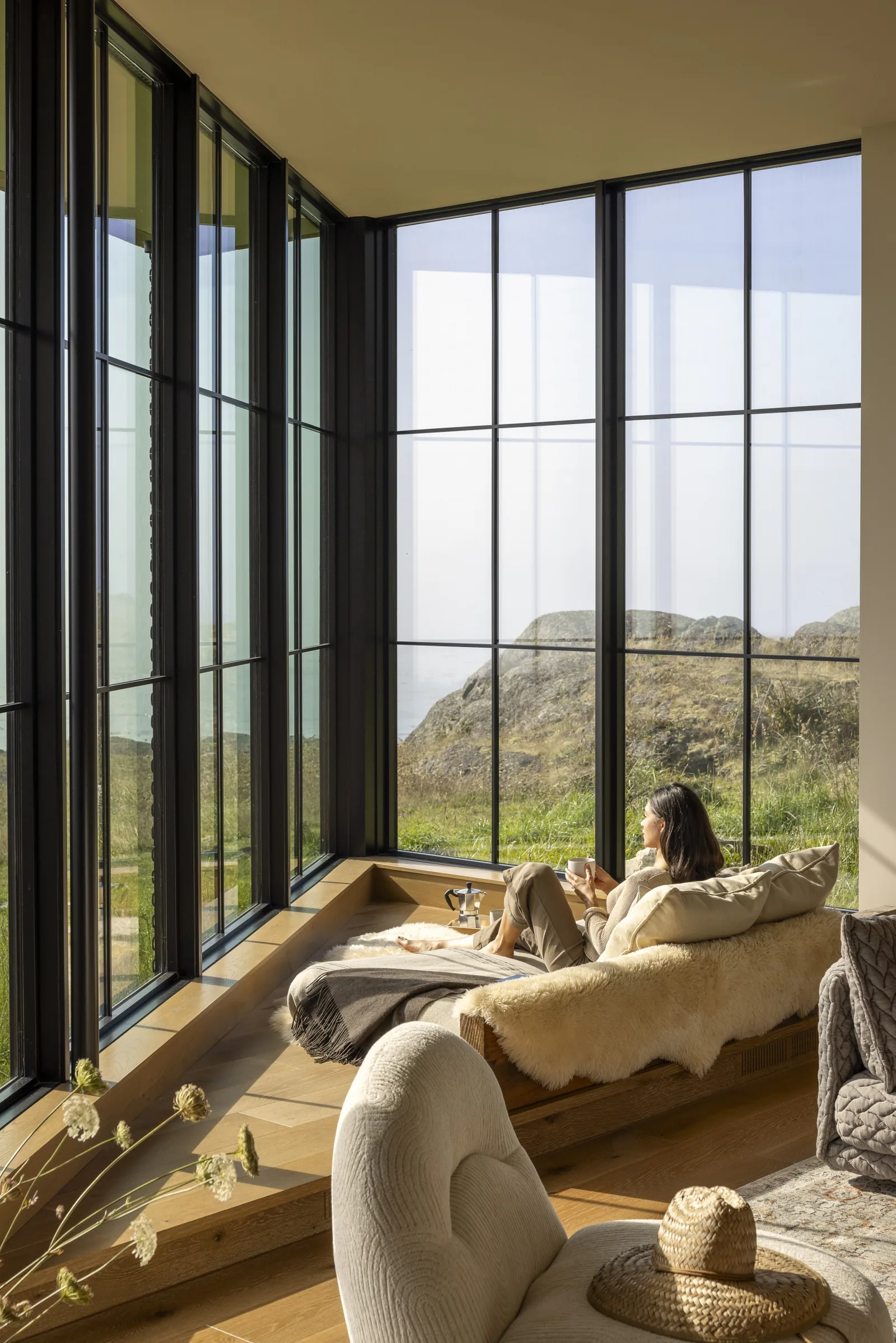 Interior seating area with floor-to-ceiling windows providing a view of rocky terrain and shrubbery outside.