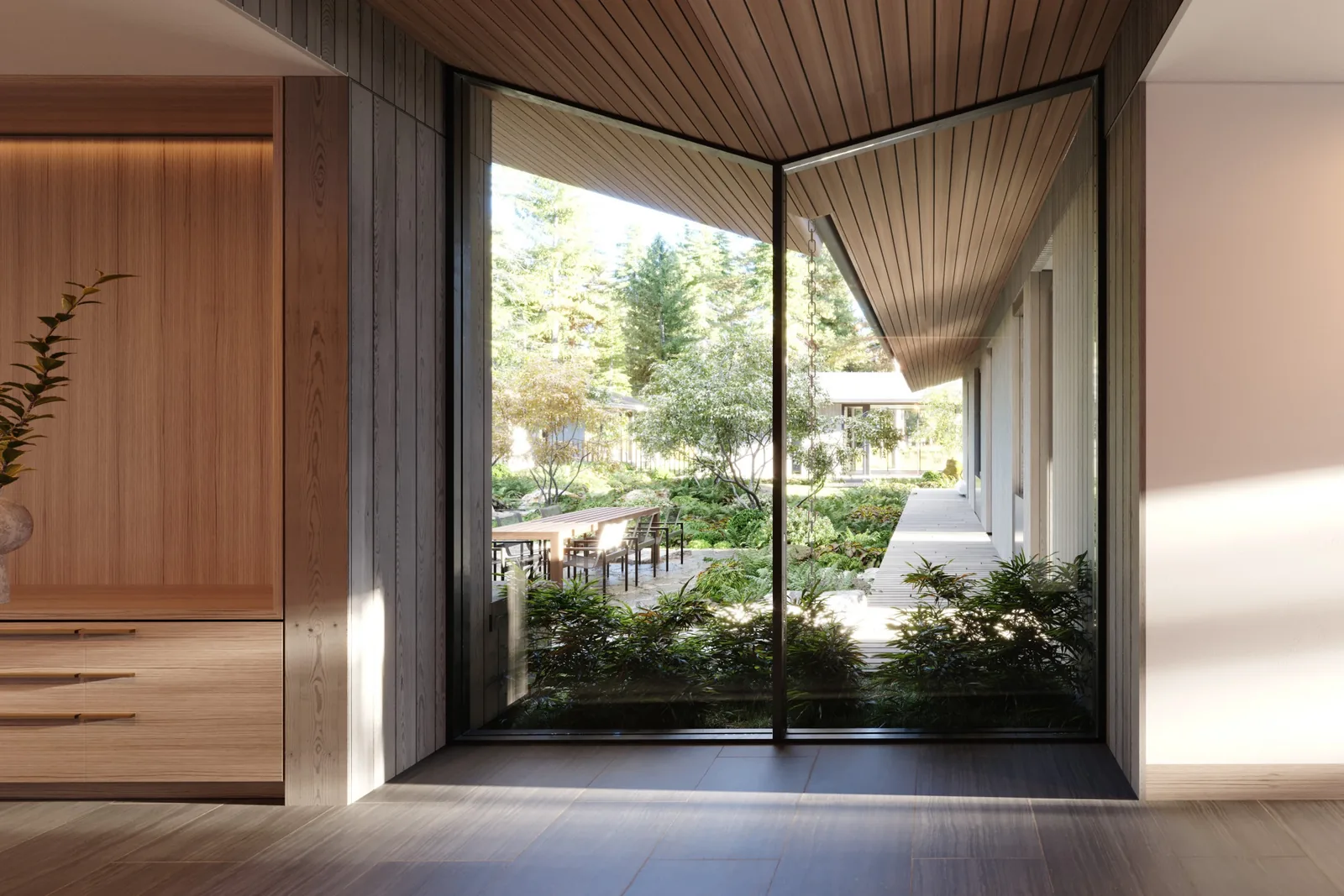 Daylit view from inside to landscaped courtyard with seating area visible through floor-to-ceiling glazing.