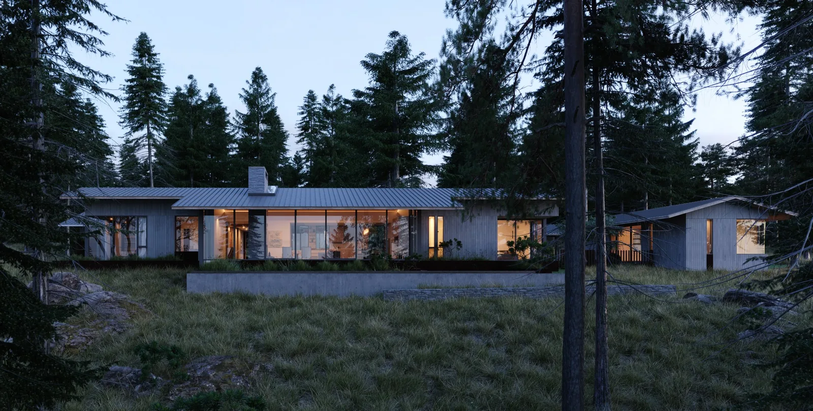 Exterior front view of a modern house with large glazing and metal roofing in a forested setting at dusk.