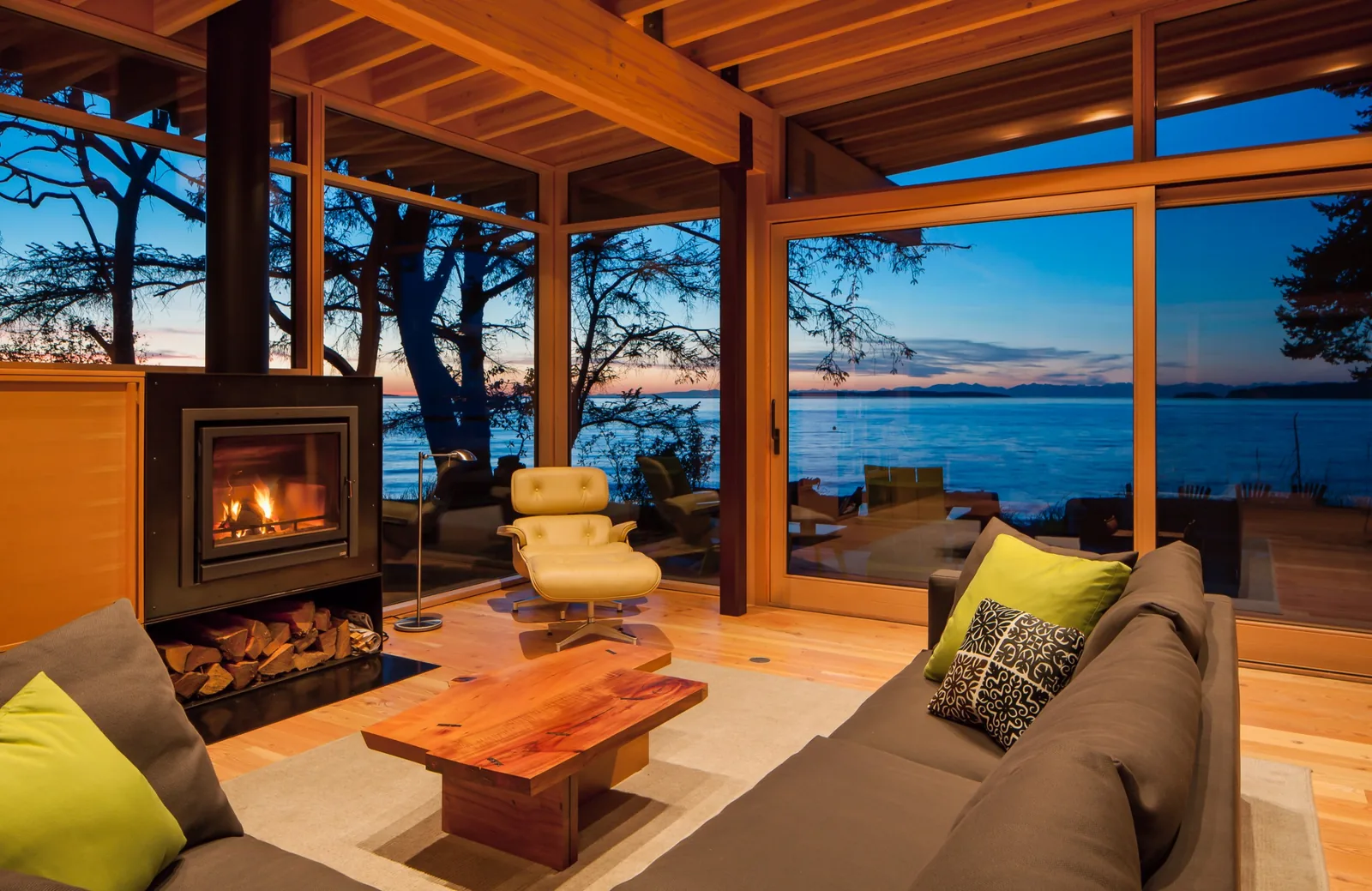 Interior living room with large windows overlooking the ocean during sunset.