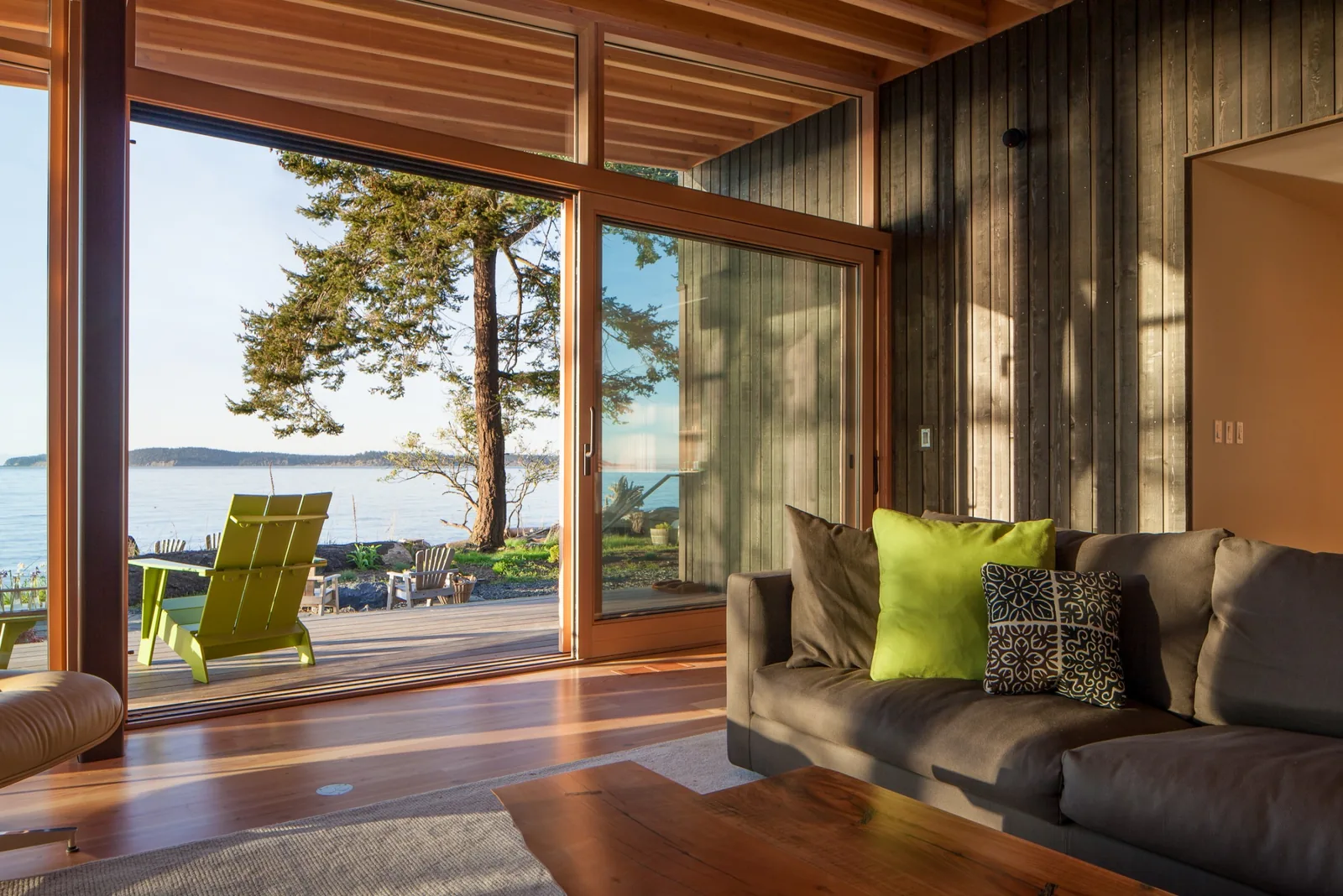 Interior living room with floor-to-ceiling sliding glass door providing water views and natural light.