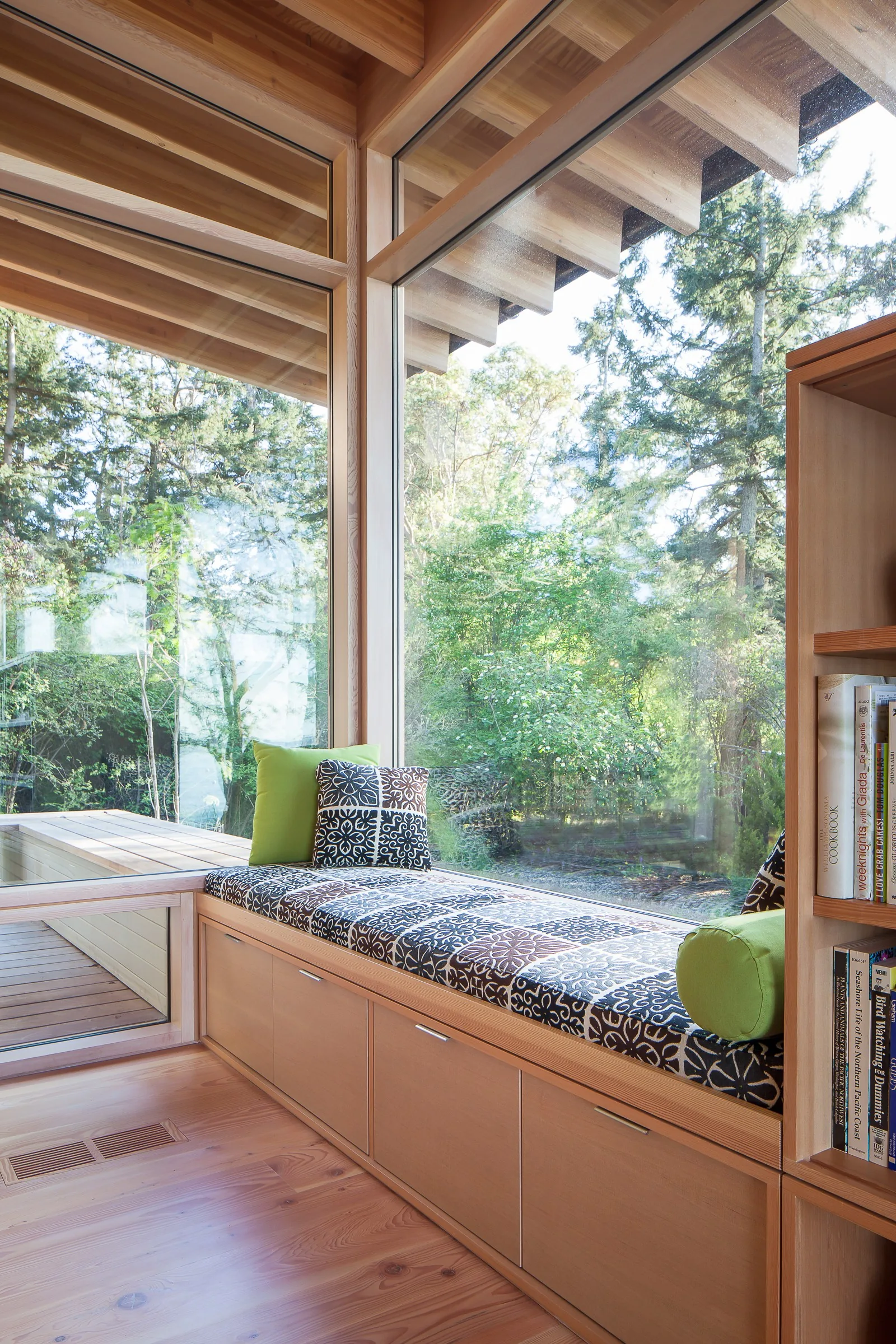 Window seat with storage beneath is positioned at a corner with expansive glazing overlooking the landscape.