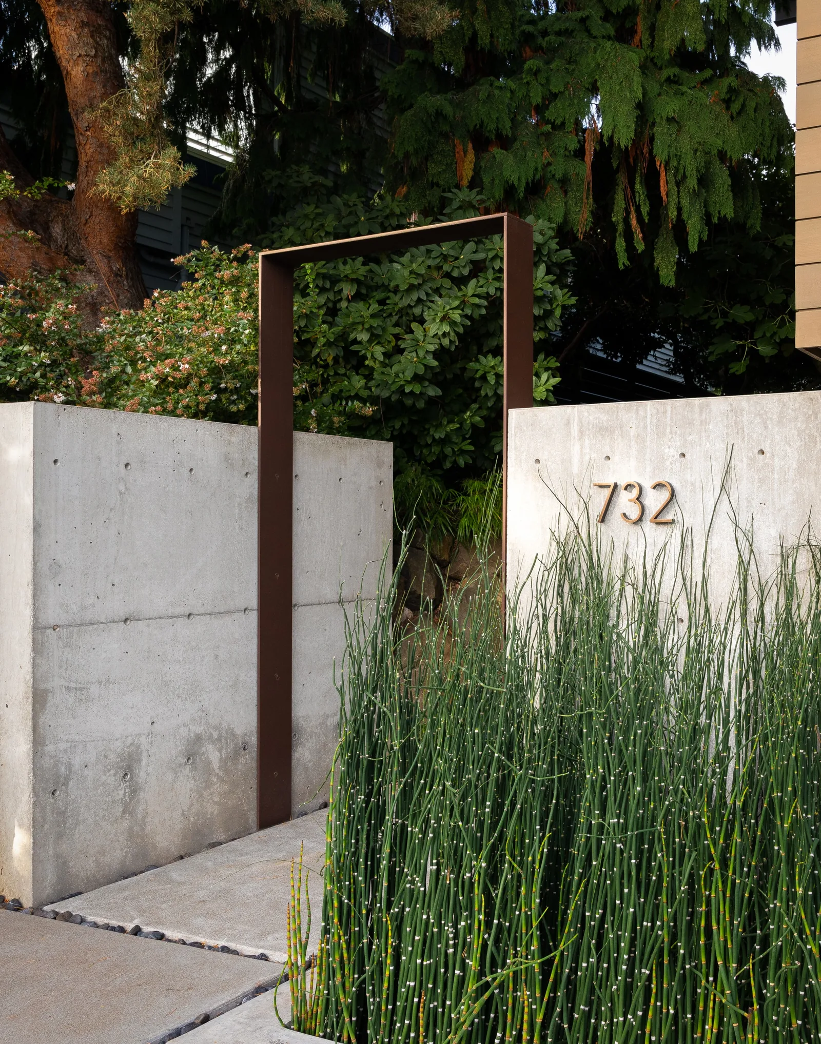 Entry gate featuring a tall metal frame and concrete walls with house number 732.
