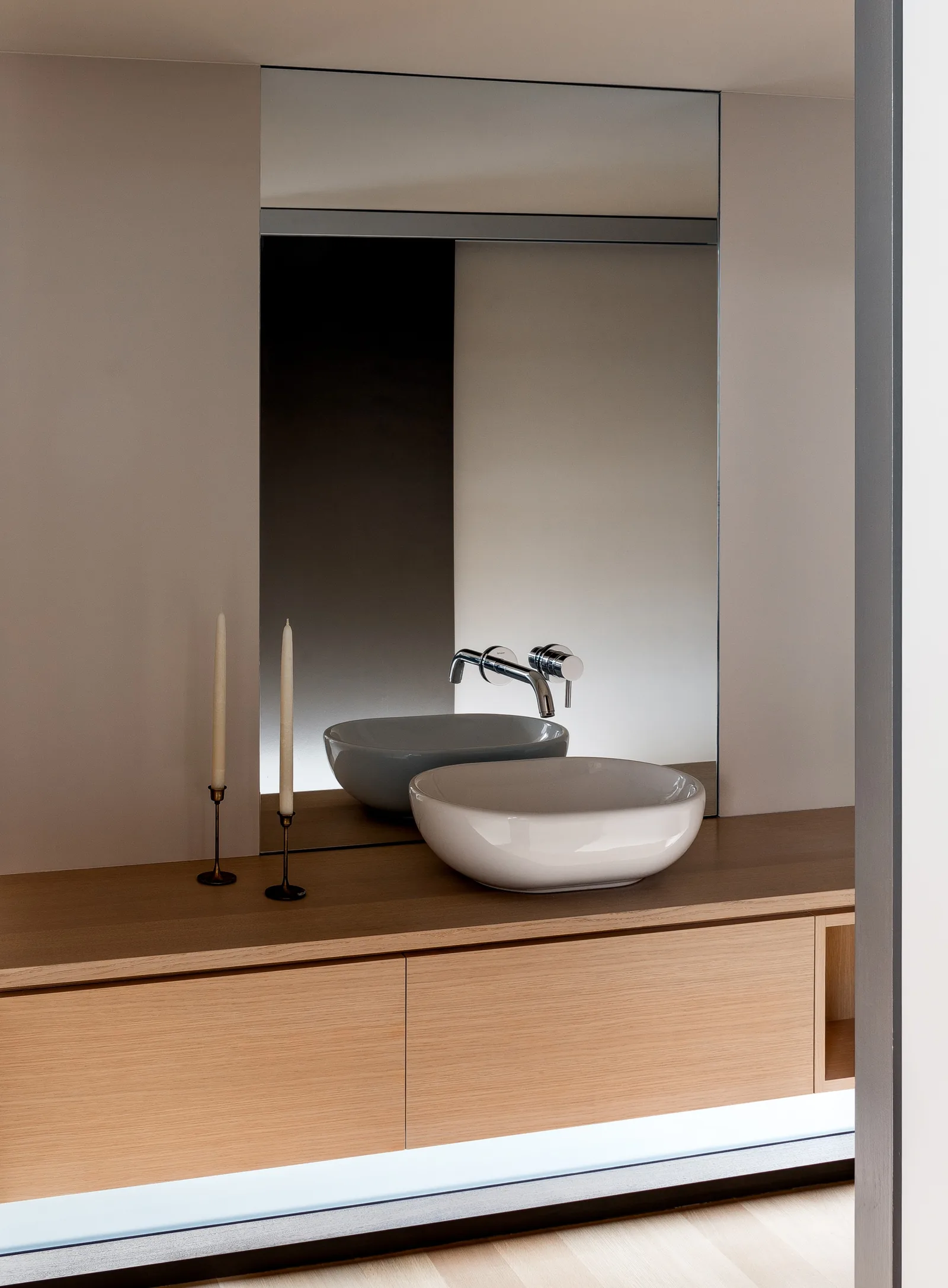 Bathroom vanity area with a vessel sink, wall-mounted faucet, floating wood cabinetry, and a large rectangular mirror.