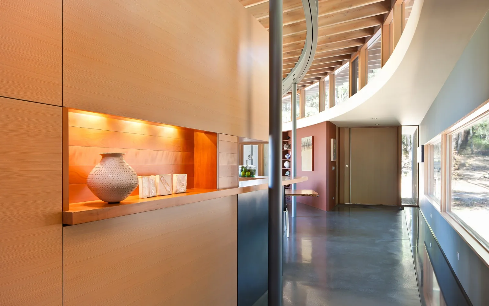 Curved hallway ceiling with exposed wood beams and built-in wood niche illuminated by recessed lighting.