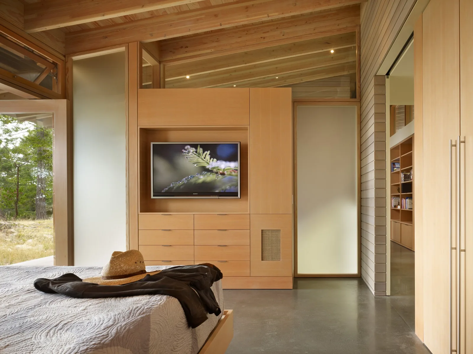 Bedroom interior featuring wood cabinetry with integrated TV and frosted glass panels.