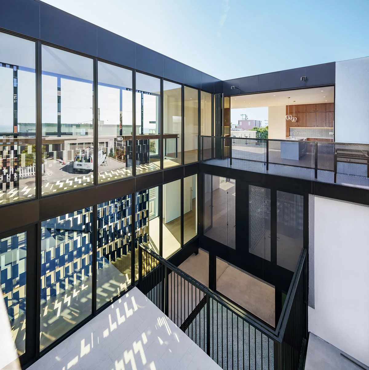 Modern residential switch house with a central courtyard surrounded by glass facades and metal balcony railings.