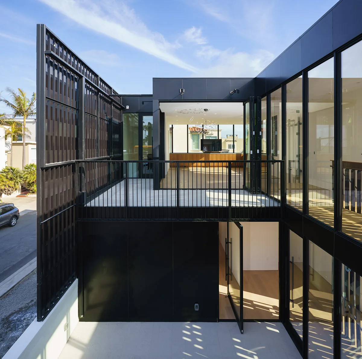 Second-floor exterior balcony with black steel railing and large glass folding doors overlooking the street.