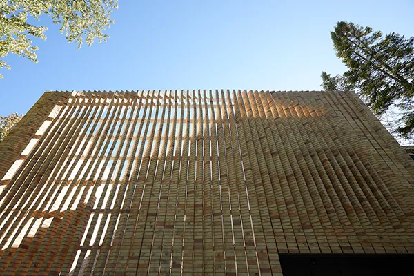 The Lipton Thayer House features a curved brick facade with vertical brick slats and a flat roof, designed by Brooks + Scarpa Architects.