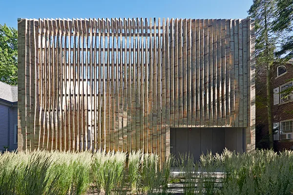 The Lipton Thayer House features a textured facade of vertical brick slats with a flat roof and dense green grasses at the front.