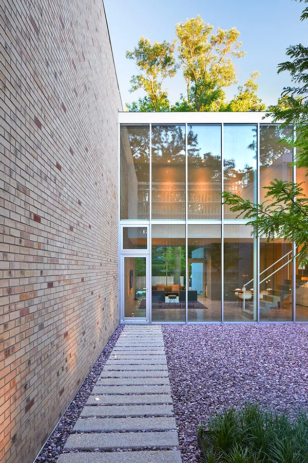 The Lipton Thayer House features a textured brick facade contrasting with expansive glass walls and a flat roof.