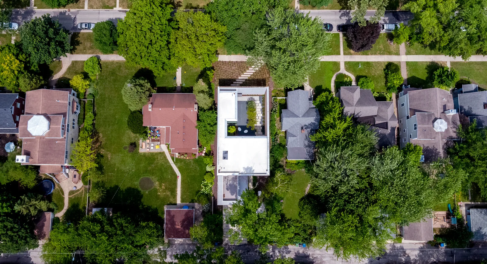 The Lipton Thayer House, a modern flat-roofed home, is centered in a leafy residential area with neighboring traditional houses.