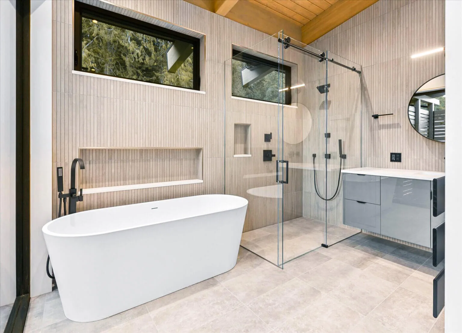 Bathroom featuring a freestanding tub, a glass shower enclosure, and a floating vanity with a round mirror.