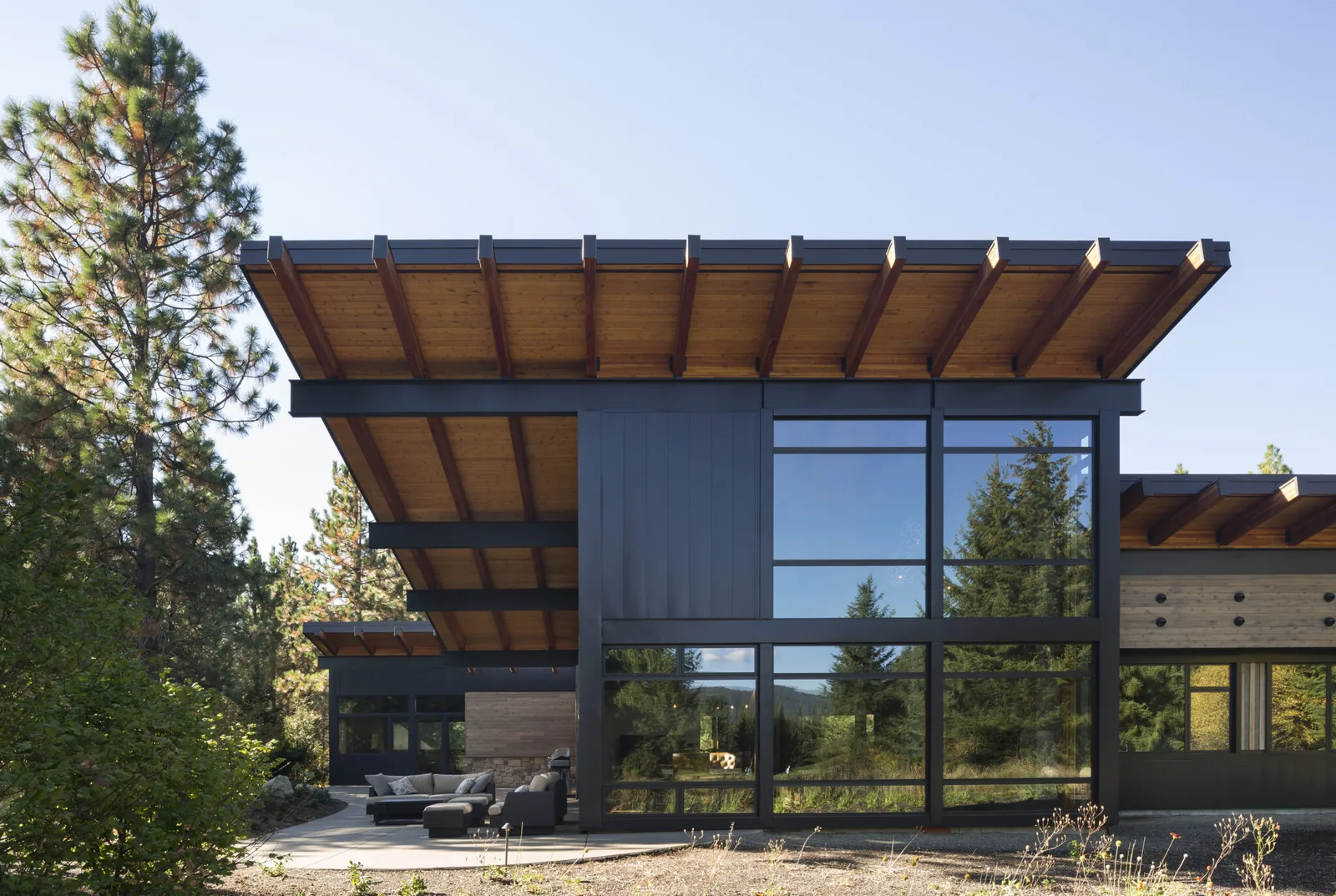 Exterior front view of a modern house featuring large glass panels and an extended flat roof with exposed beams.