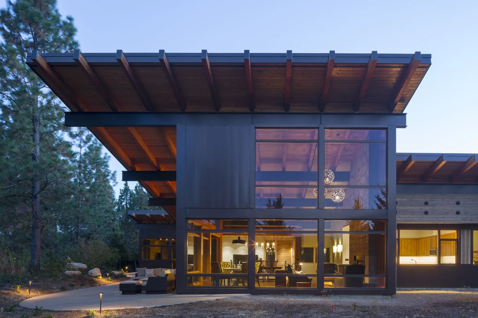 Exterior front view of a modern architectural house with extensive glazing and wooden roof structure.