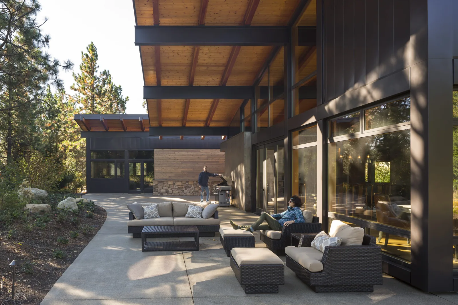 Modern home's covered patio with wood ceiling, large windows, and outdoor seating area.