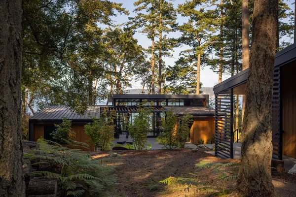 Cape San Juan residence by Prentiss Balance Wickline features wood siding and metal roofing within a wooded landscape.