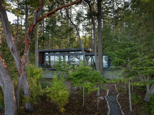 The Cape San Juan project features a modern glass exterior surrounded by mature trees and nature views.
