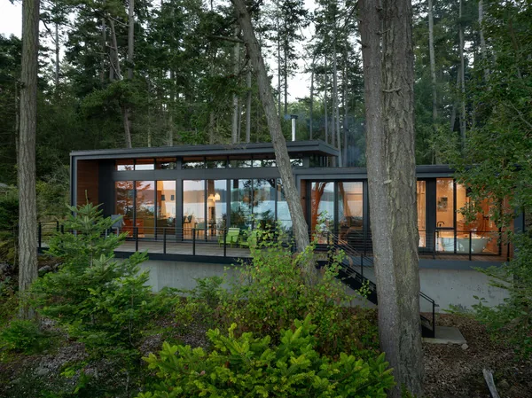 The Cape San Juan house features expansive glass walls and a minimalist railing, blending indoor and outdoor spaces.