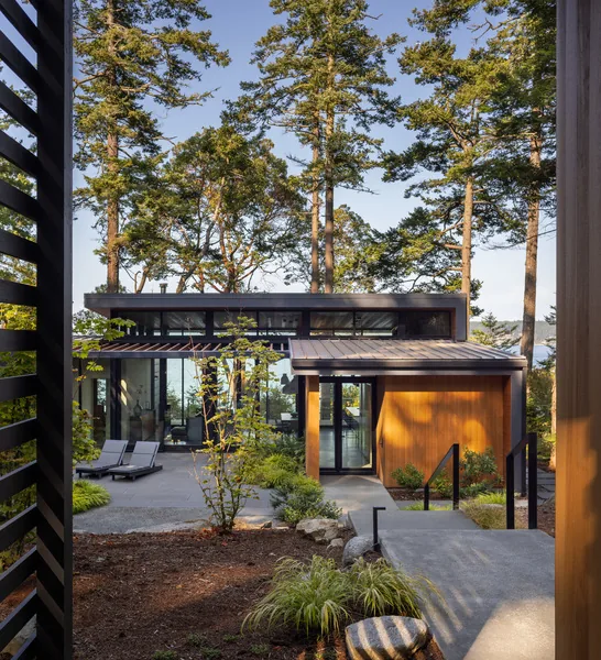 The Cape San Juan project features large windows and a wooden pergola surrounded by trees and outdoor lounge chairs.