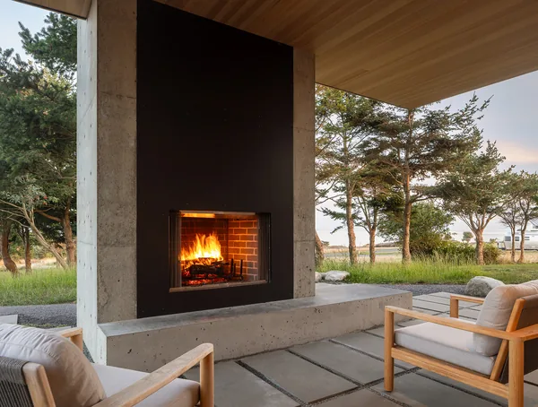 Outdoor patio area featuring a concrete fireplace with metal surround and wooden ceiling.