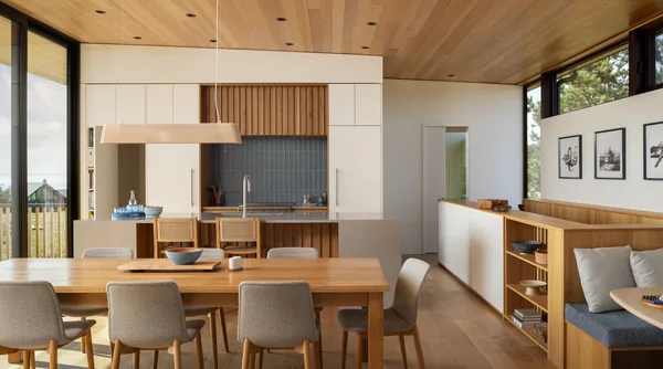Open dining and kitchen area with wood finishes, large windows, and built-in seating.