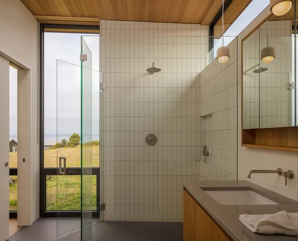 Bathroom with walk-in shower and wood ceiling showing a glass door opening to an exterior view.